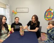 Therapists. with children sitting and playing jenga in the consult room