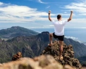 Trail runner man celebrating his success after hiking up the mountains
