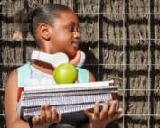 school girl with backpack, headphones and books at school entrance.