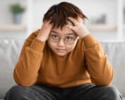 Stressed chinese boy looking at camera, home interior | OCD in Children
