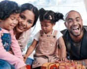 Portrait of a happy family playing together with wooden toys at home