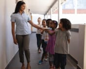 Schoolkids with teacher standing in row in hallway