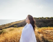 a young handsome asian woman wrapped in a white sheet on a field