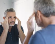mature man looking in bathroom mirror