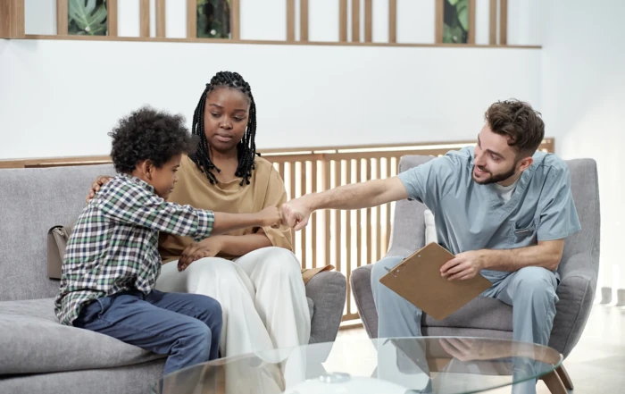 Therapist greeting a child with a fist bump during a family therapy session, showing trust-building and support for mental health treatment in New Jersey.