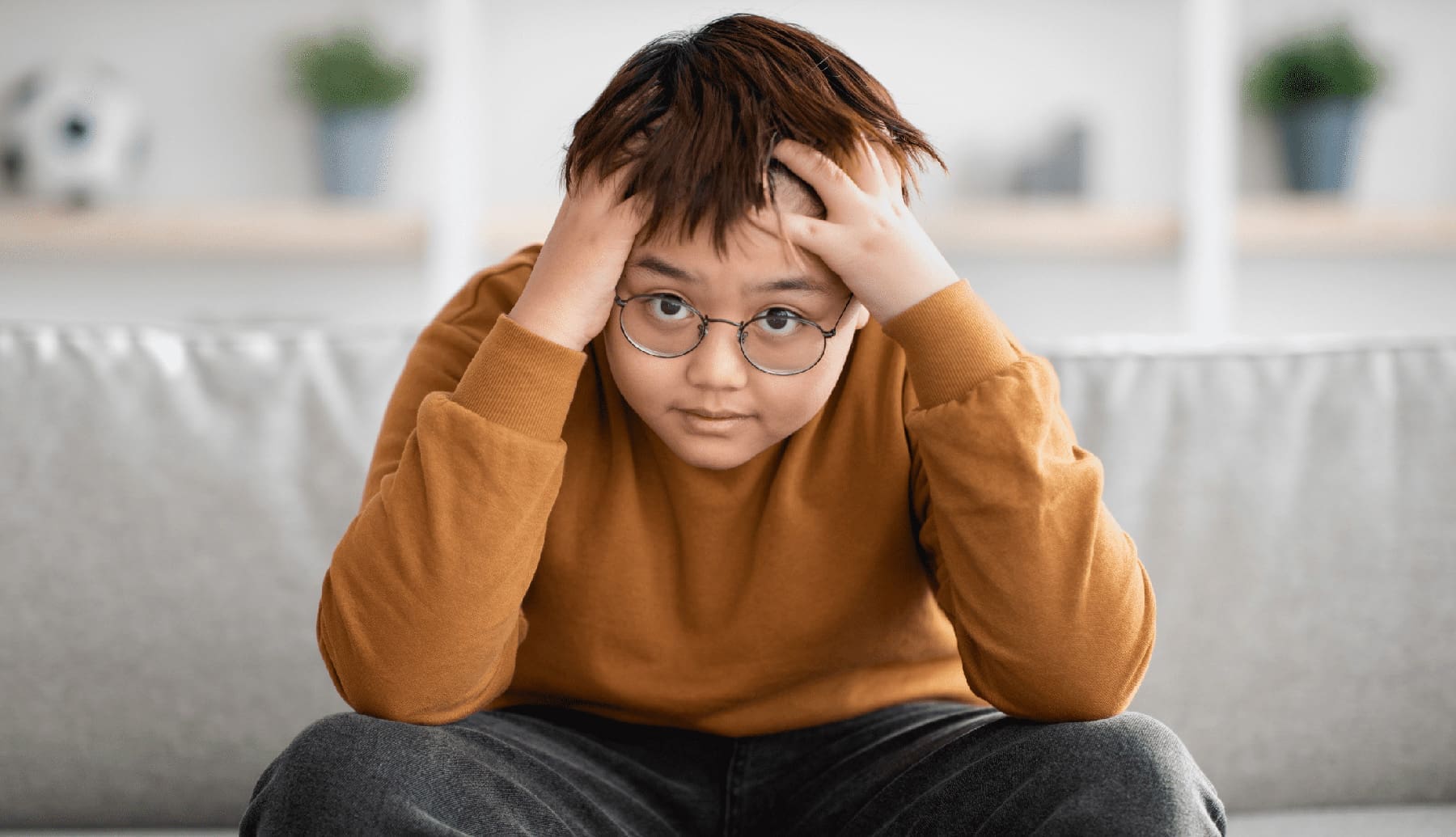 Stressed chinese boy looking at camera, home interior | OCD in Children