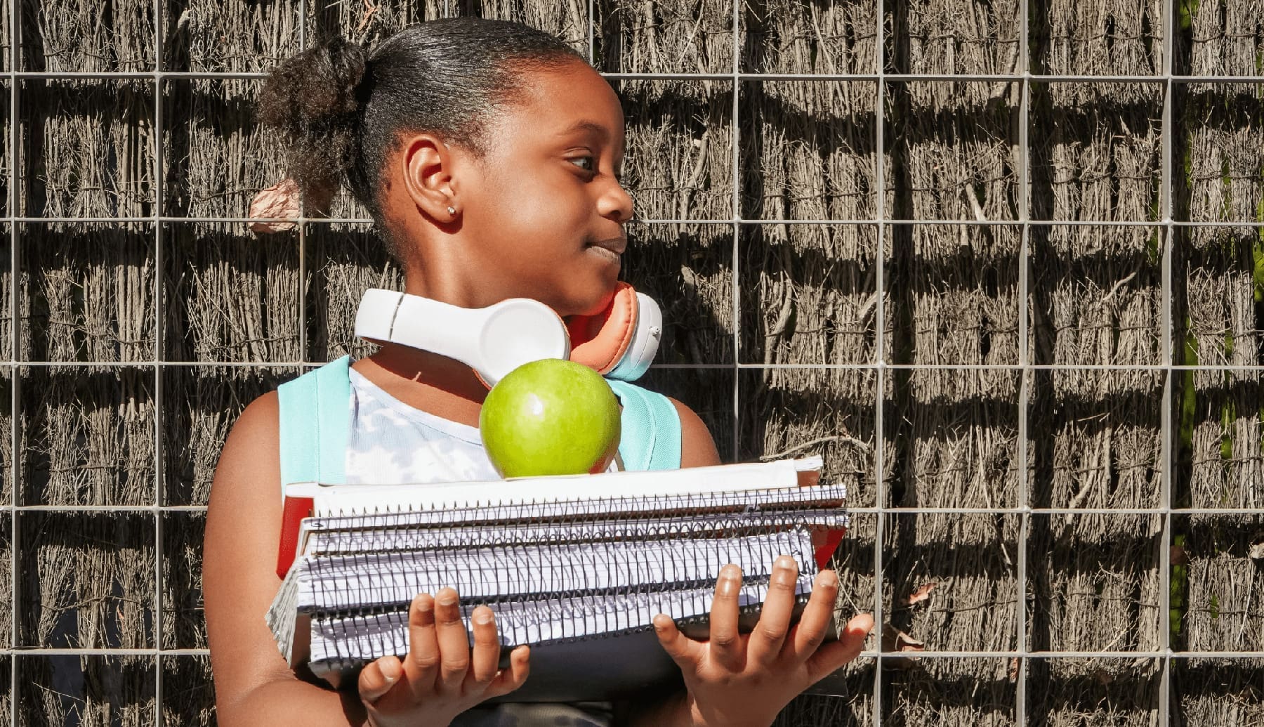 Navigating the Back-to-School Transition with Ease school girl with backpack, headphones and books at school entrance.