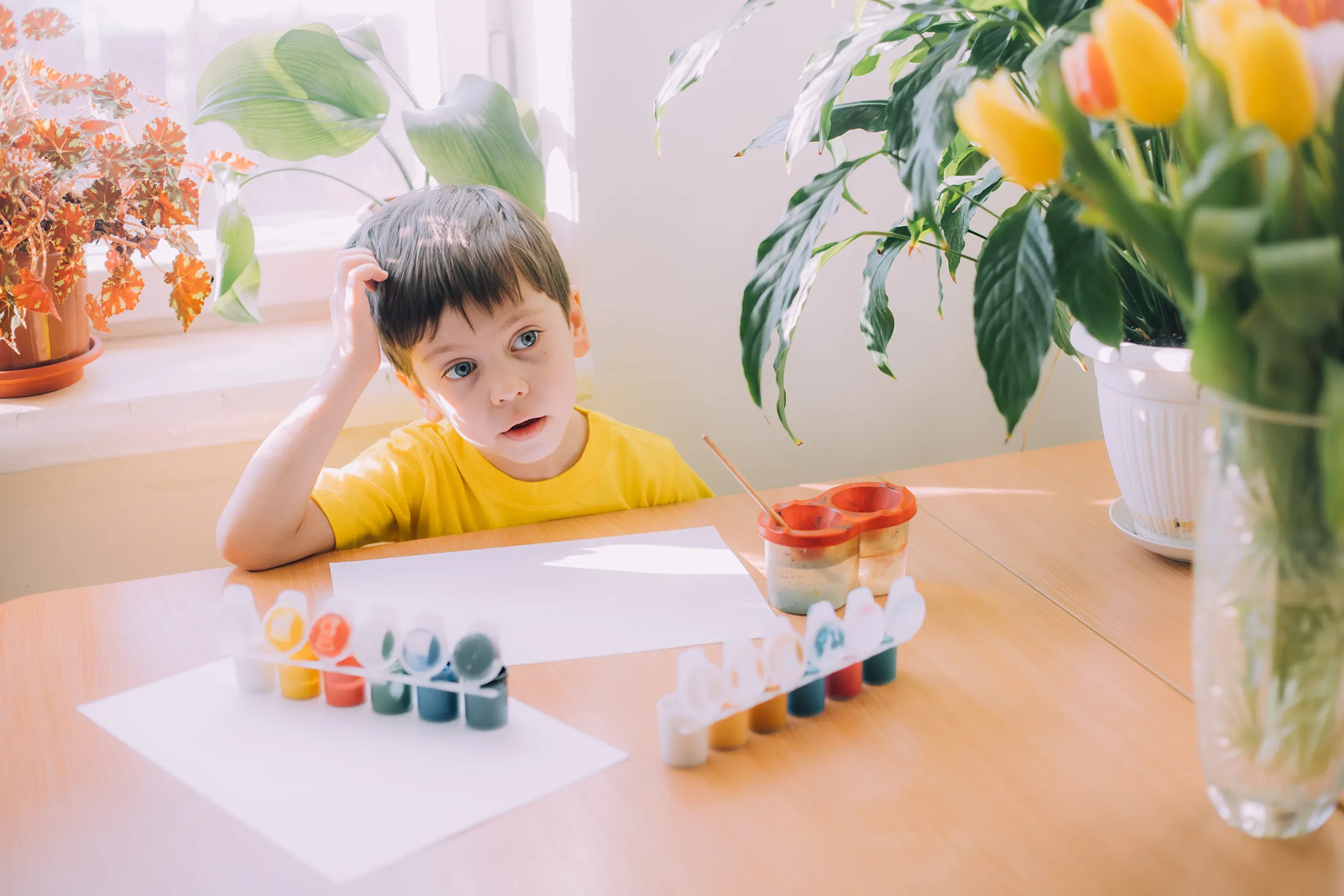 Child sitting at a table looking tired while painting, illustrating signs baby is sick and the importance of visiting a pediatrician in McKinney to check for developmental or health concerns.