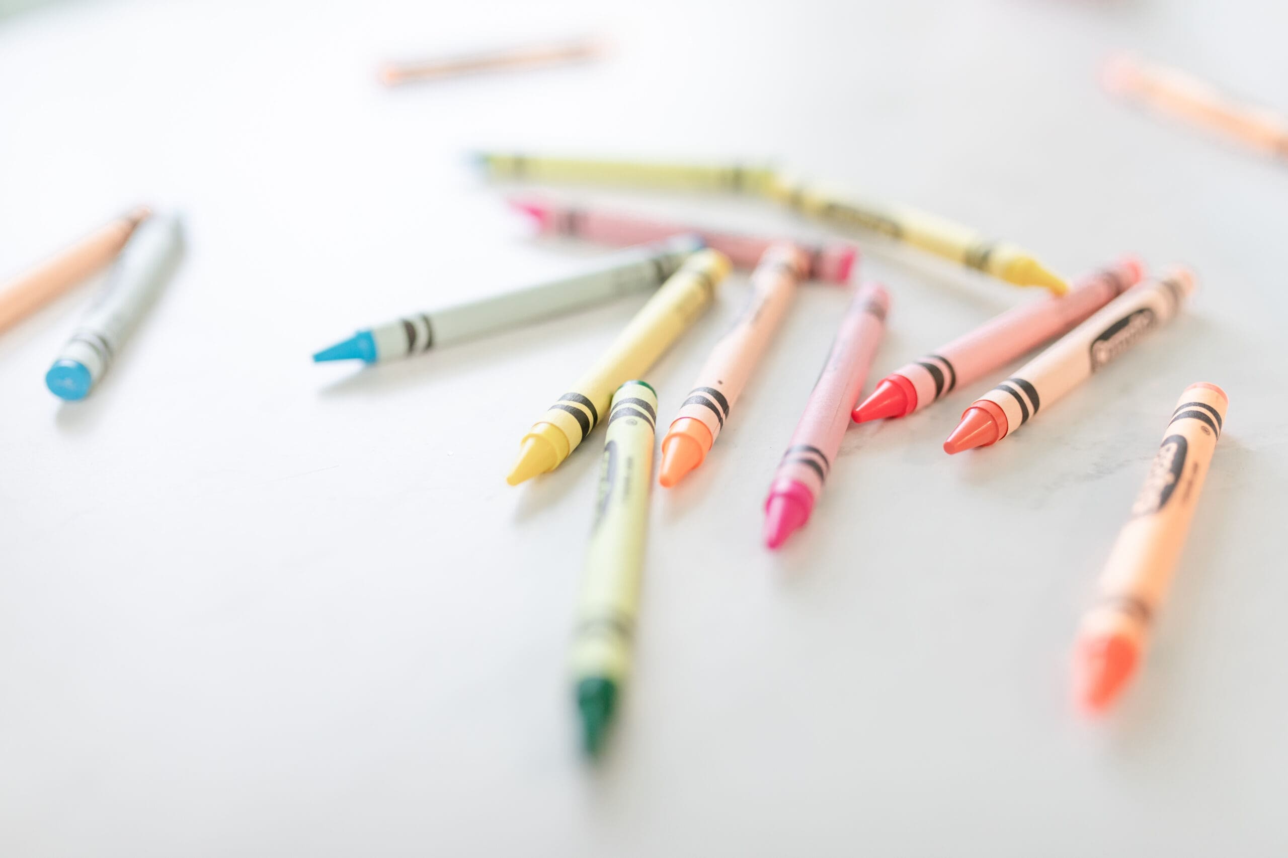 Art-Making Materials – Colorful Crayons Colorful crayons scattered on a white surface, representing art-making and creative expression